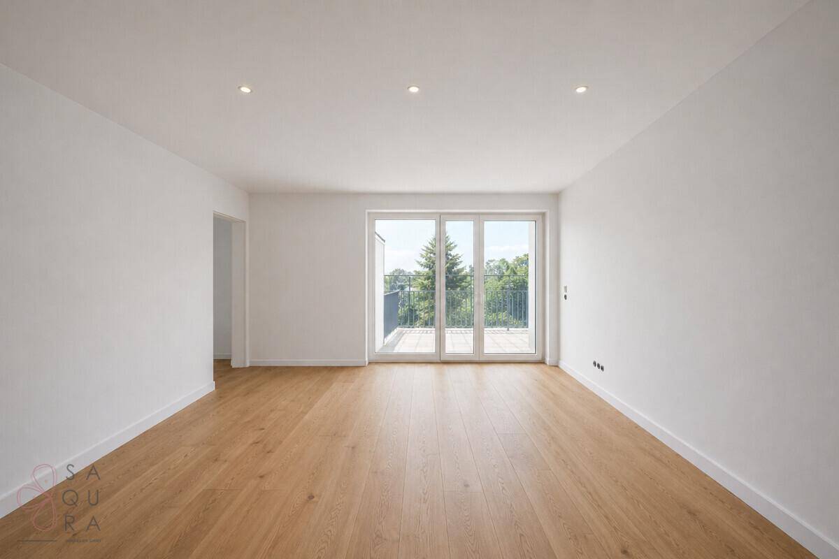 Geräumiger, heller Raum mit Holzboden und großen Fenstern, die auf einen Balkon führen.