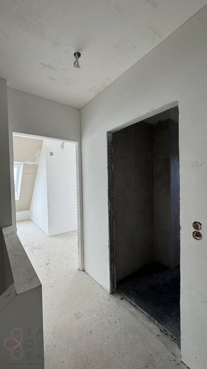 Flur im Rohbau mit vorbereitetem Aufzugschacht und Zugang zu weiteren Etagen.