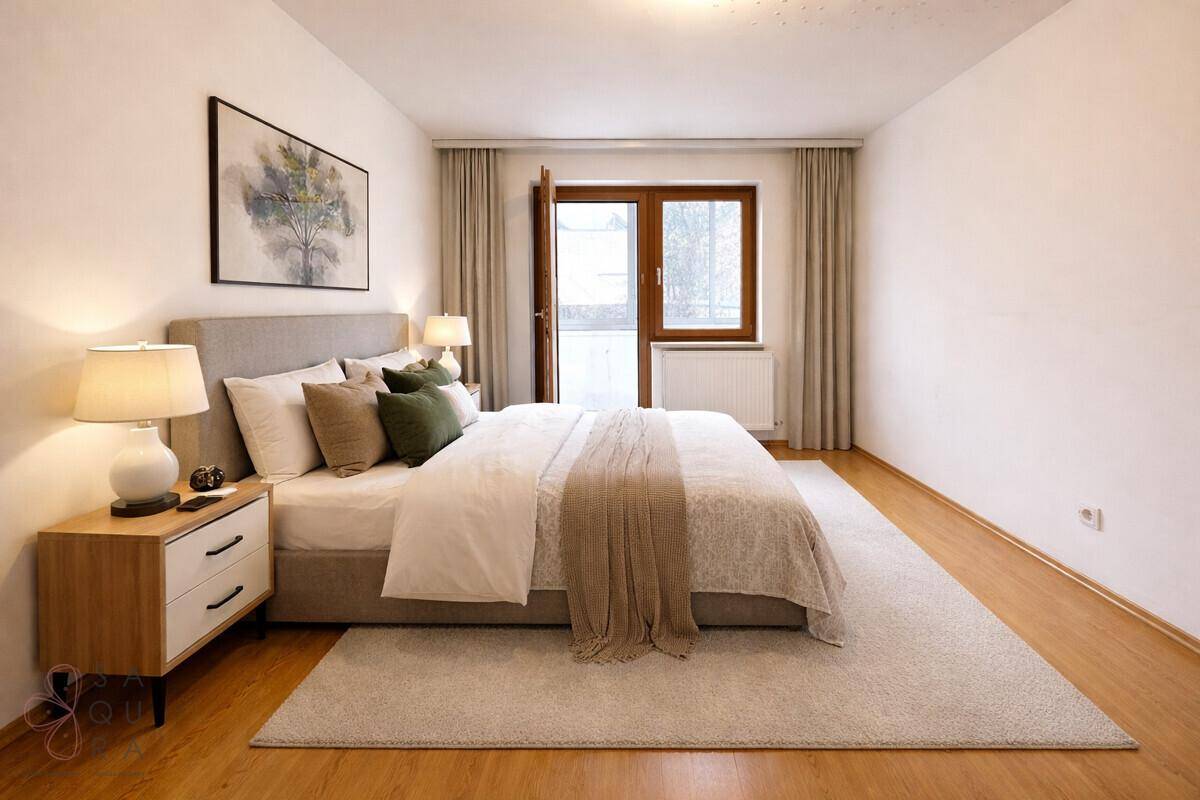 Helles Schlafzimmer mit Holzboden, großem Bett und Zugang zu einem Balkon.