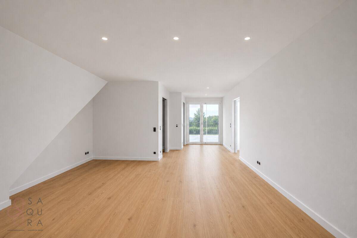 Langer, heller Raum mit Holzboden, Dachschräge und Zugang zu einem Außenbereich.