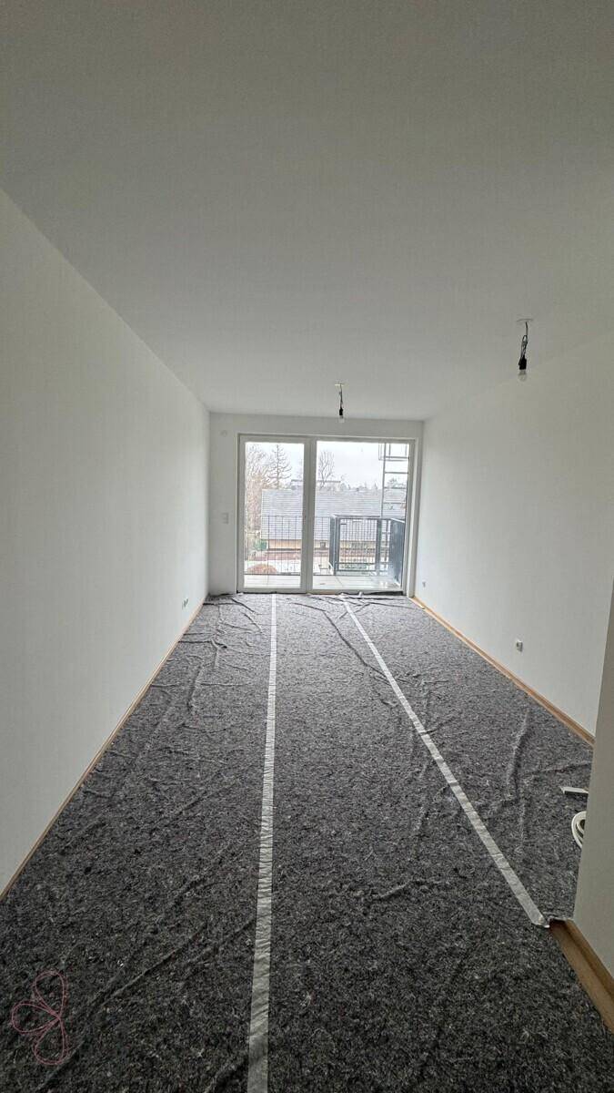Geräumiger, unmöblierter Raum mit großen Fenstern und direktem Zugang zu einem Außenbereich.