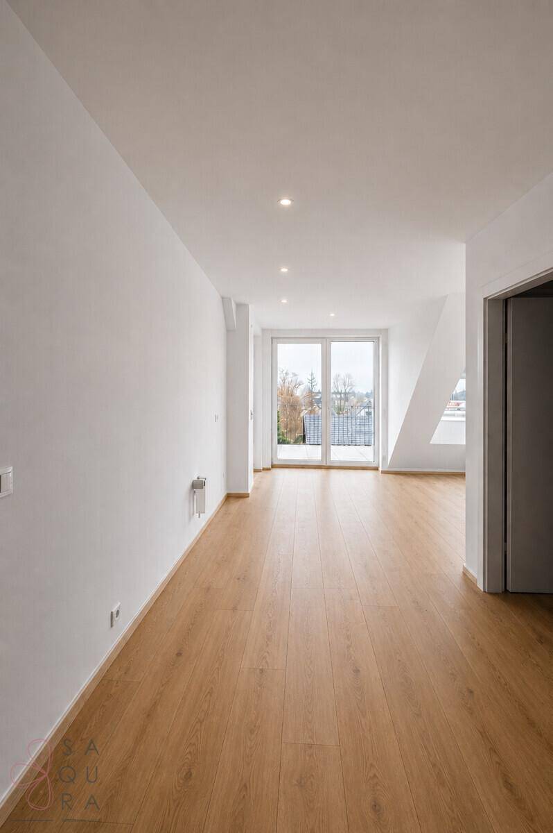 Heller Flur mit Holzboden und Zugang zu einem Außenbereich, im Hintergrund eine Dachschräge.