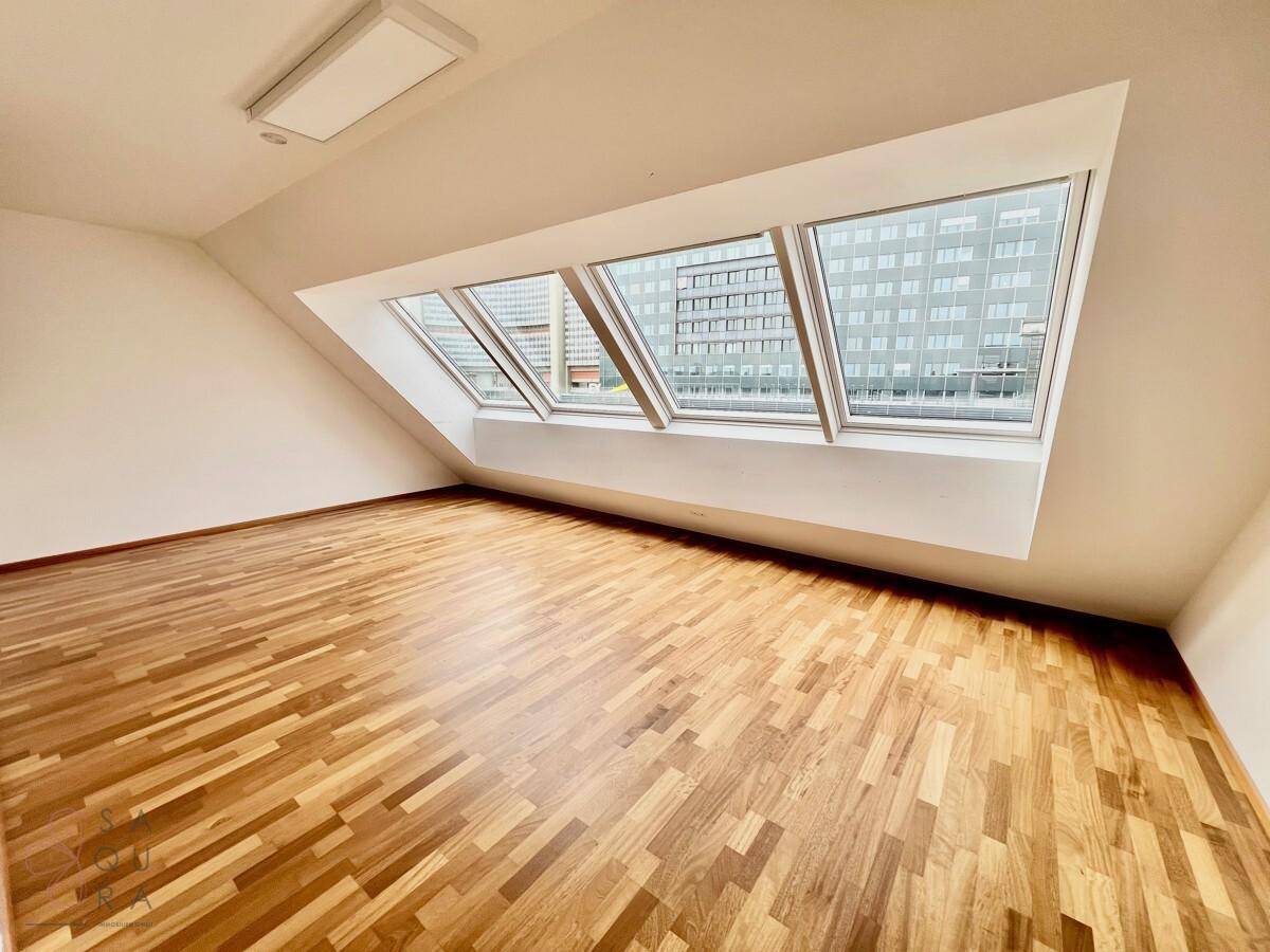 Geräumiges Schlafzimmer mit Holzboden, Dachschrägen und großen Dachfenstern, die den Raum lichtdurchfluten.