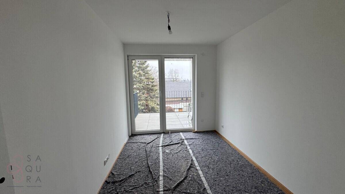 Raum im Bauzustand mit Balkonzugang und vorbereitetem Unterboden, bereit für den Endausbau.
