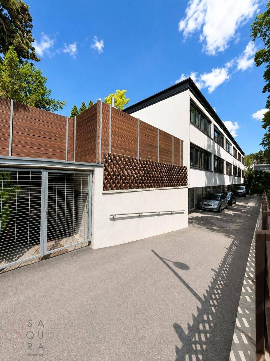 Seitenansicht des Gebäudes mit Parkbereich und einer modernen Holzverkleidung.