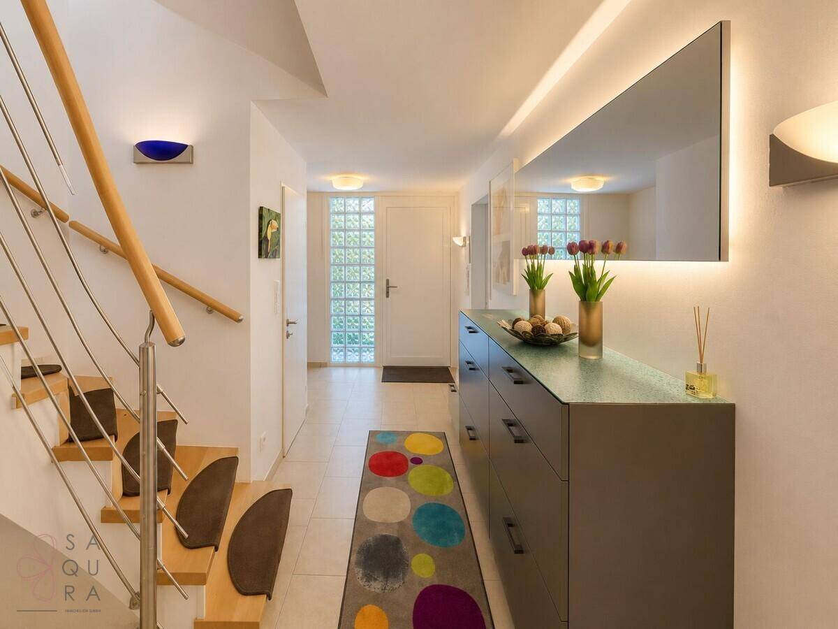 Heller Flur mit großem Spiegel, Kommode und Zugang zur Treppe.