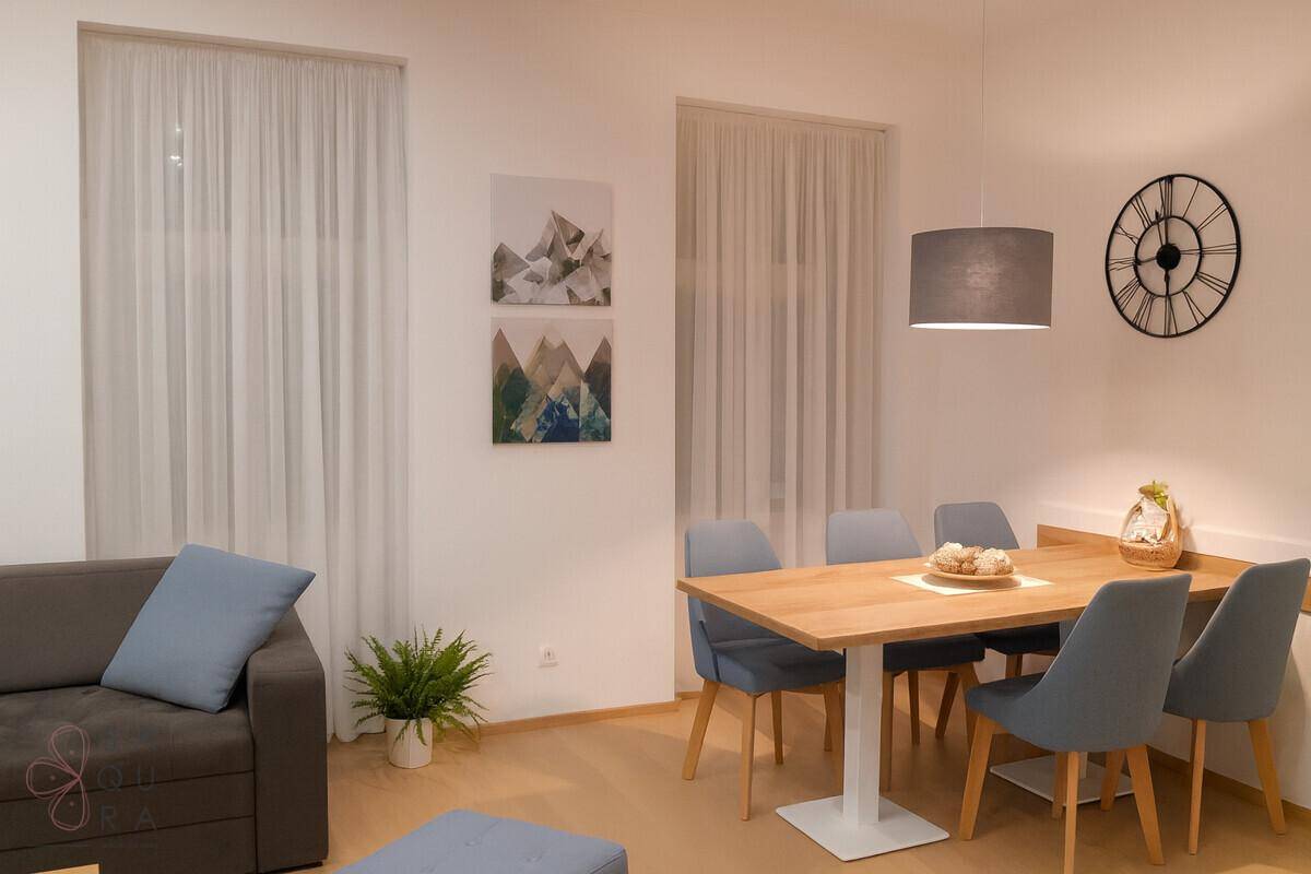 Essbereich mit modernem Holztisch, grauen Stühlen und dekorativen Bildern an der Wand.