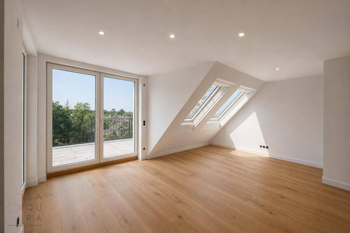 Geräumiges, leeres Wohnzimmer mit Holzboden, Dachschrägen und großen Fenstern zur Terrasse.
