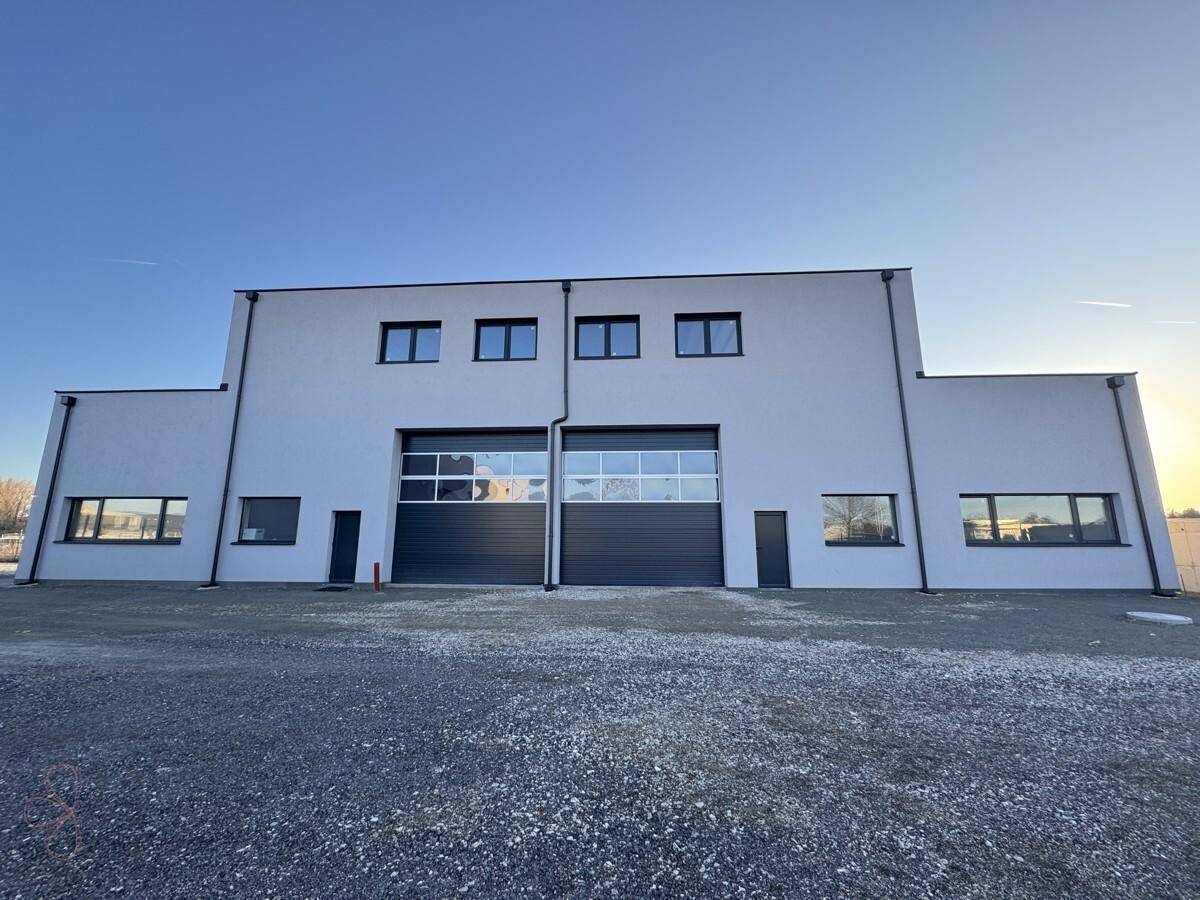 Vorderansicht von zwei modernen Industriegebäuden mit Rolltoren und Fenstern im Obergeschoss.