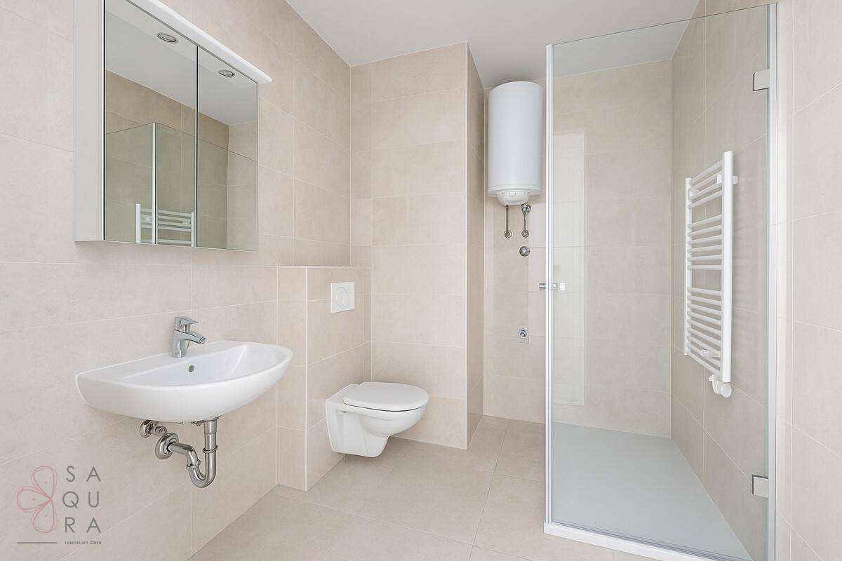 Modernes Badezimmer mit beigefarbenen Fliesen, wandhängendem WC und ebenerdiger Dusche.