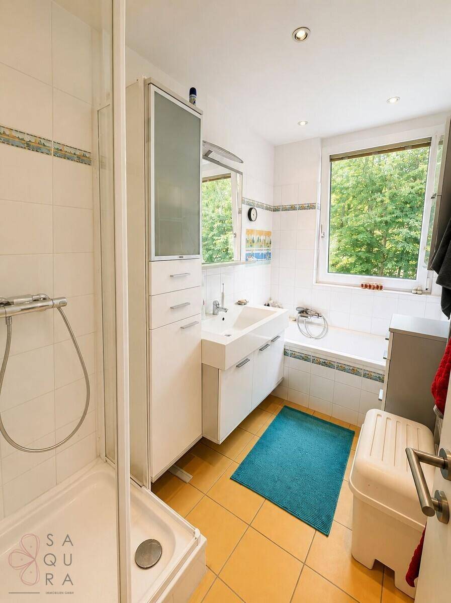 Helles Badezimmer mit Dusche, Badewanne, Waschbecken und Fenster.