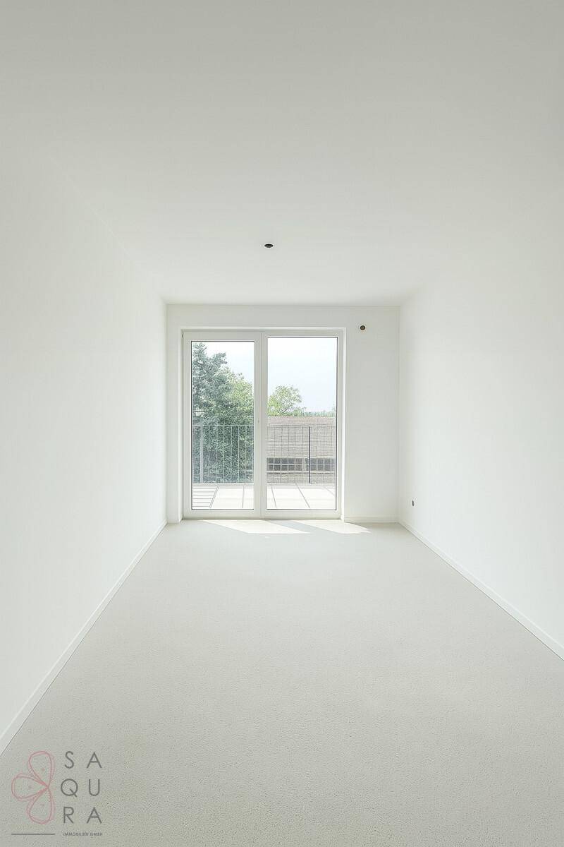 Heller, leerer Raum mit hellem Vinylboden und Zugang zu einem Balkon.