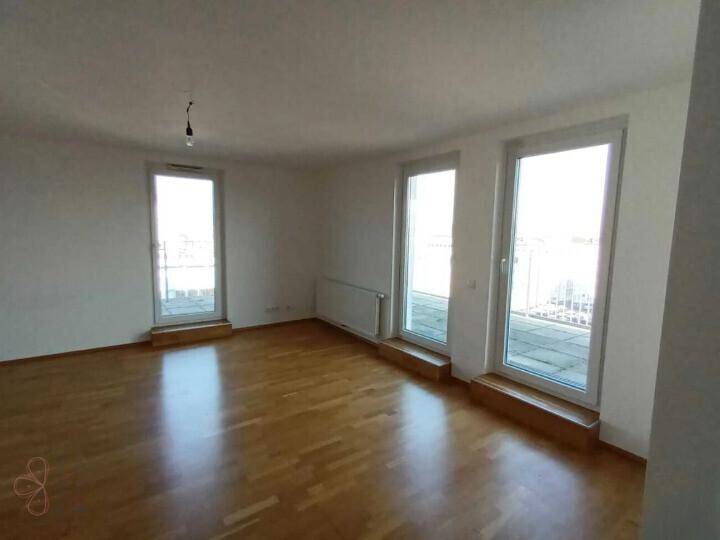 Lichtdurchfluteter Wohnbereich mit Parkettboden und großen Fenstern, die viel Tageslicht hereinlassen.