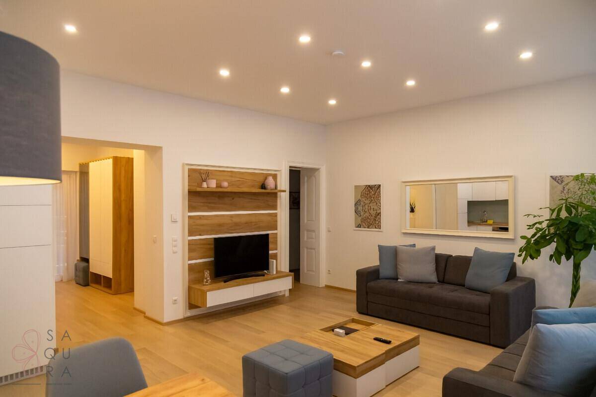 Gemütliches Wohnzimmer mit TV-Wand, Sofas und Zugang zu weiteren Räumen, hell und modern.