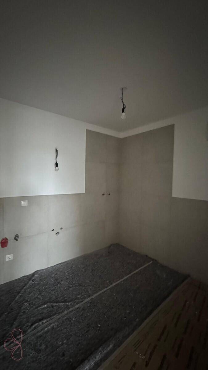 Badezimmer im Bau mit hellgrauen Fliesen und sichtbaren Anschlüssen für Sanitärinstallationen.