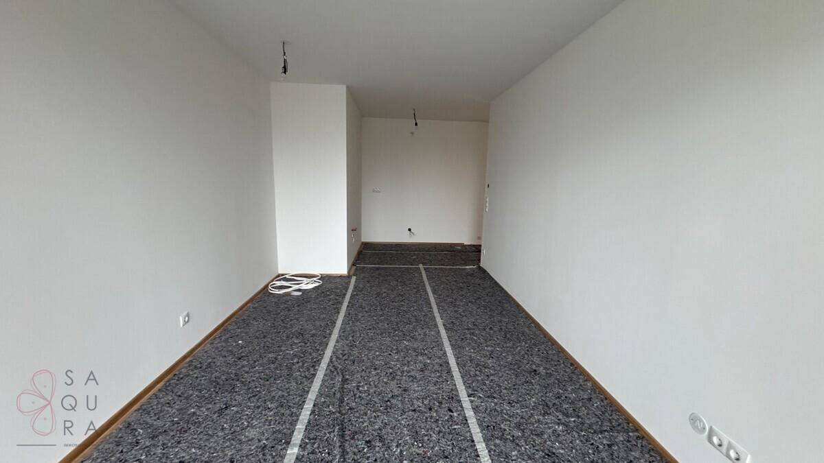 Raum im Bauzustand mit vorbereitetem Unterboden und weißen Wänden, bereit für den Endausbau.
