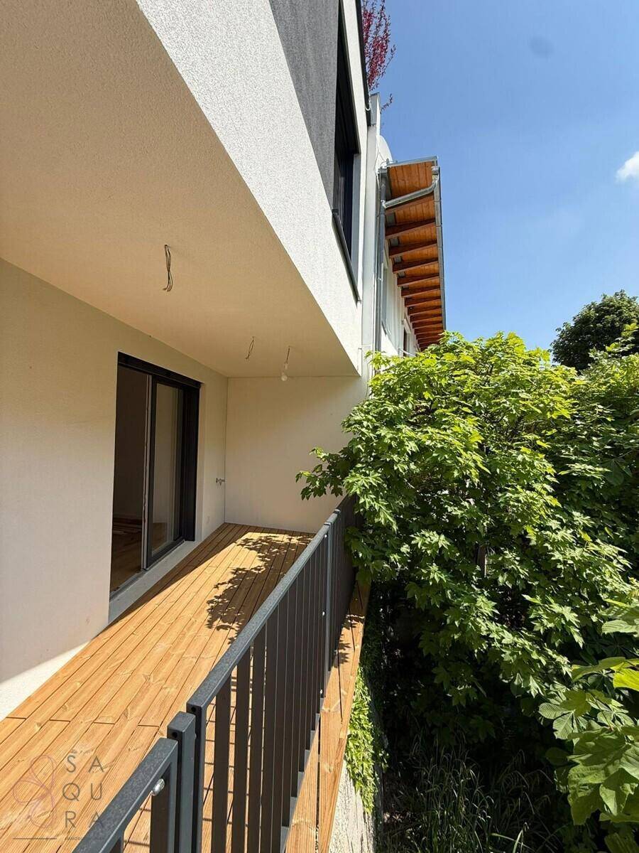 Überdachter Balkon mit Holzboden und Blick ins Grüne, ideal zum Entspannen.