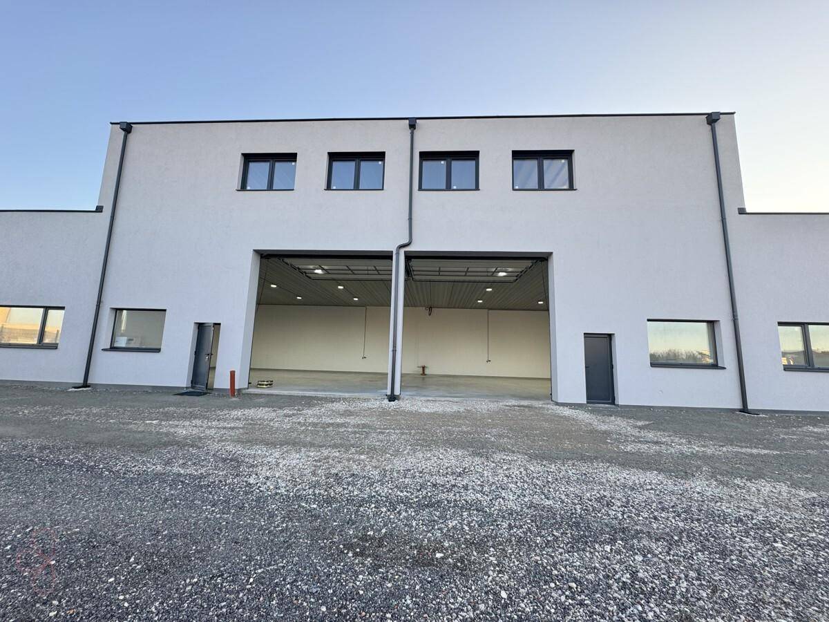 Vorderansicht von zwei modernen Industriegebäuden mit Rolltoren und Fenstern im Obergeschoss.