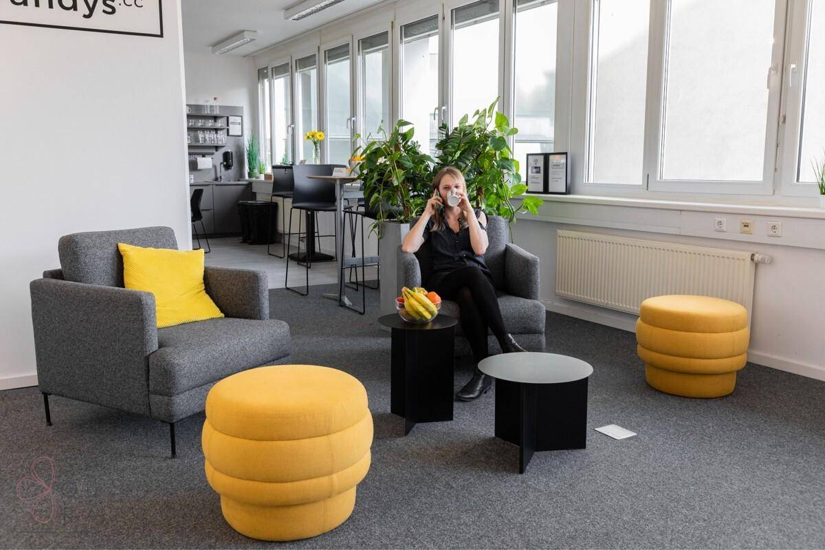 Gemütlicher Loungebereich im Büro mit bequemen Sesseln, gelben Akzenten und Blick ins Grüne.