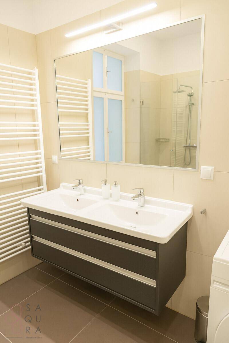 Modernes Badezimmer mit Doppelwaschbecken, großem Spiegel und beheiztem Handtuchhalter.