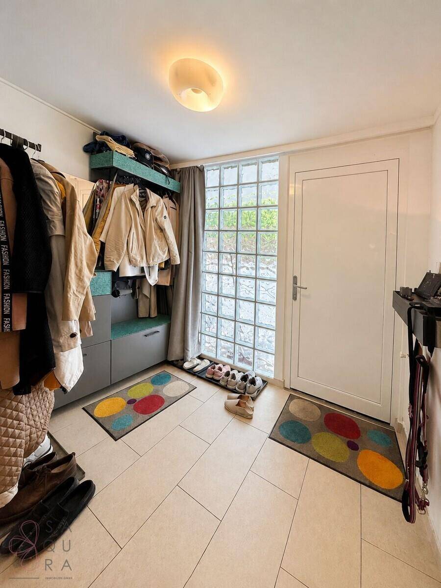 Eingangsbereich mit Garderobe, Schuhablage und dekorativem Glasbausteinfenster.
