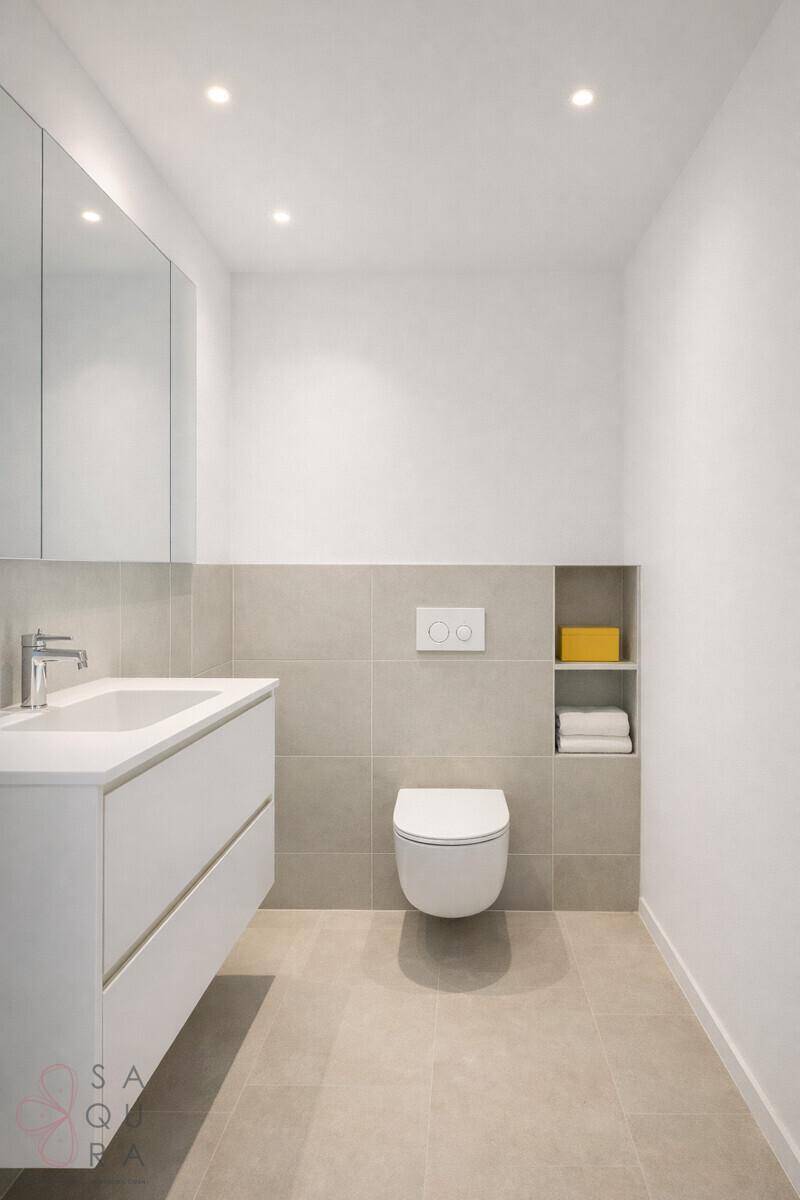 Helles Badezimmer mit Einzelwaschbecken, Wand-WC und beigefarbenen Fliesen, modern und funktional.