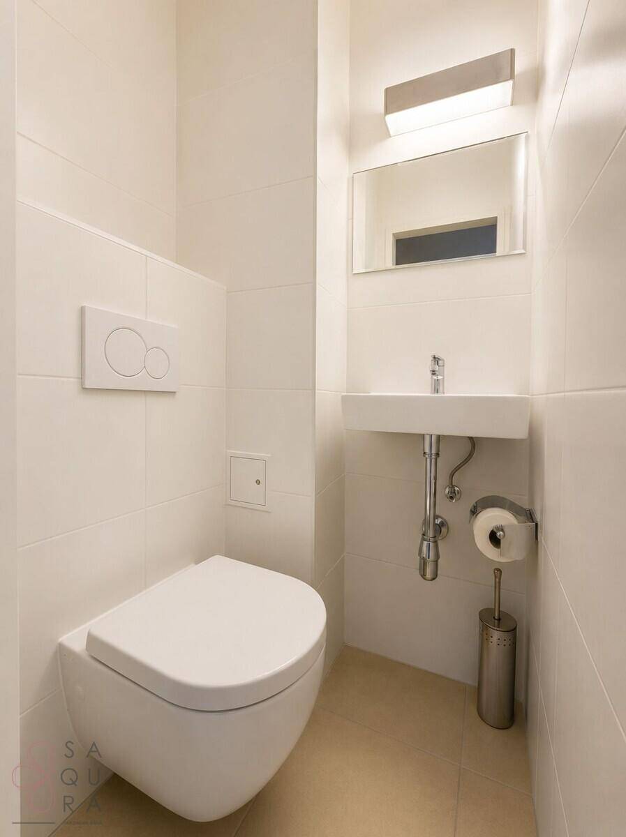 Modernes Gäste-WC mit wandhängender Toilette, kleinem Waschbecken und weißen Fliesen.