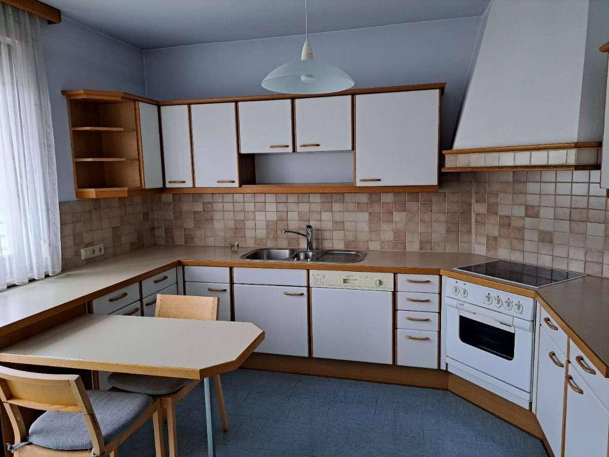 Funktionale Küche mit weißen Schränken, integrierten Geräten und Essbereich, bereit zur Nutzung.