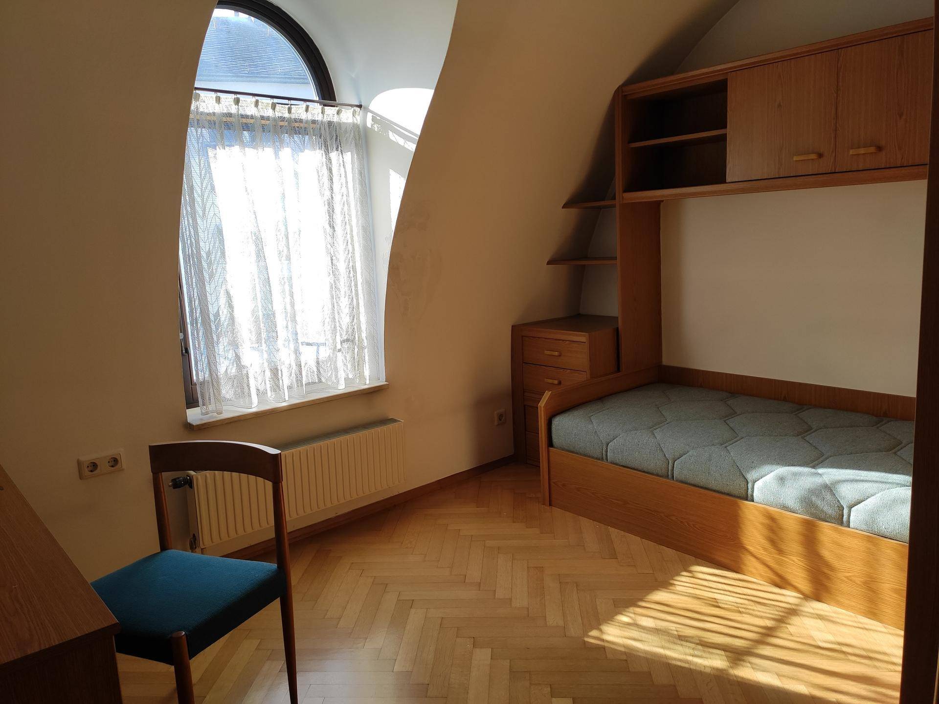 Gemütliches Schlafzimmer mit Dachschräge und Parkettboden, ausgestattet mit einem Einzelbett und Schreibtisch.