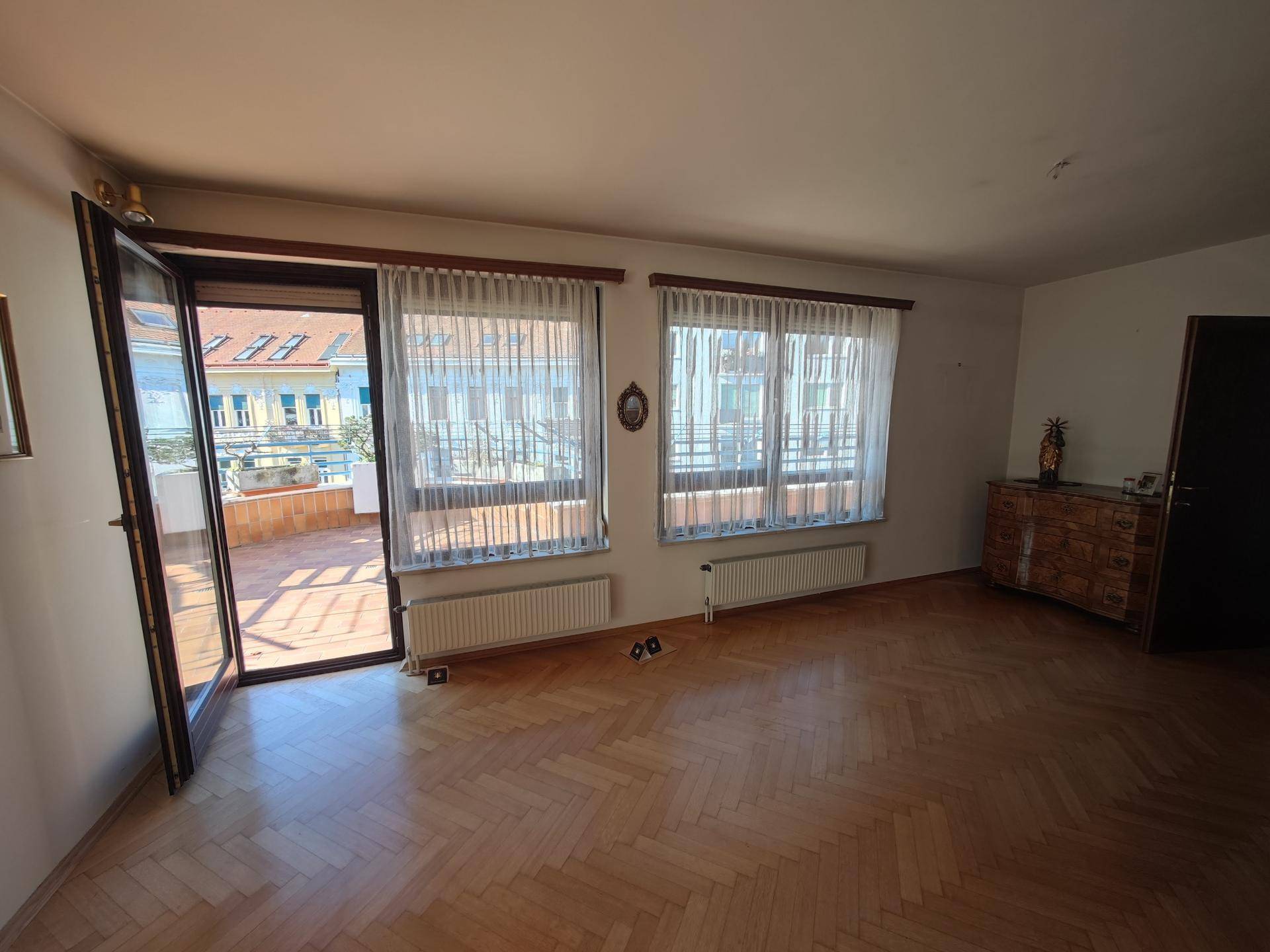 Helles Wohnzimmer mit Fischgrätparkett und direktem Zugang zur sonnigen Dachterrasse.