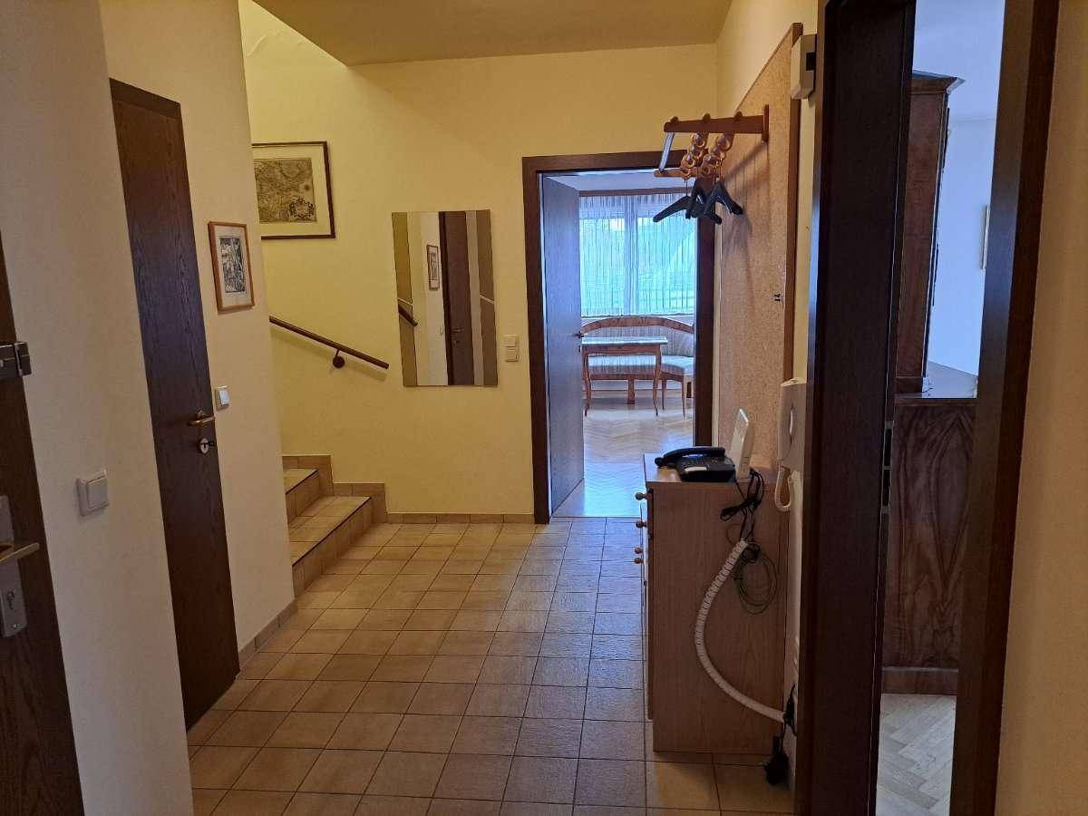 Heller Eingangsbereich mit Fliesenboden und Treppe zum Obergeschoss, bietet Zugang zu weiteren Räumen.