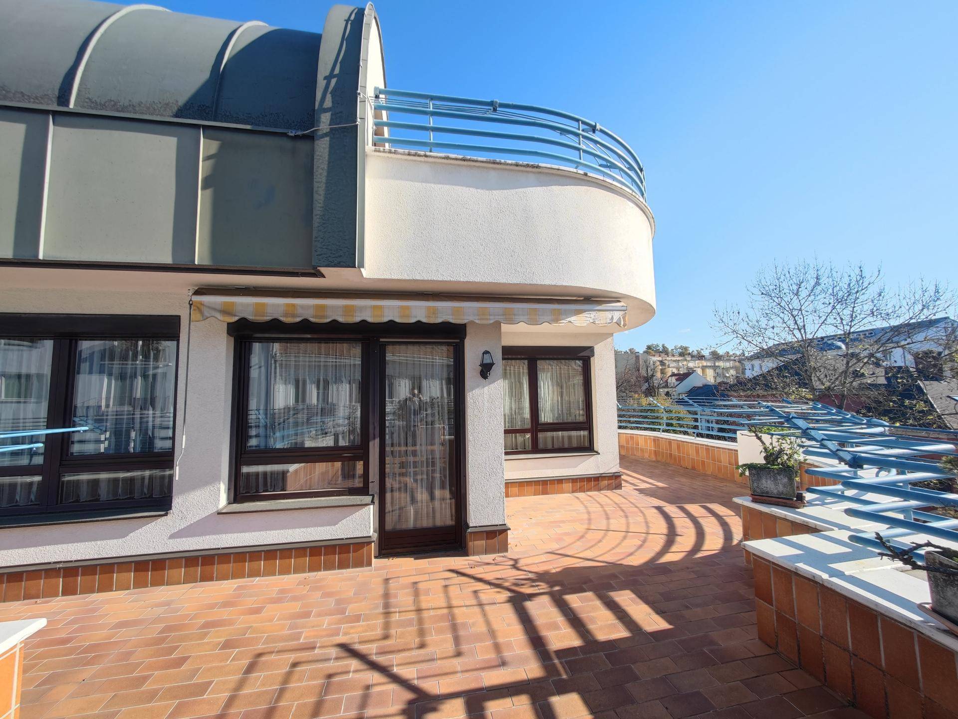 Große Dachterrasse mit Ziegelboden und Markise, bietet viel Platz für Outdoor-Aktivitäten und Entspannung.