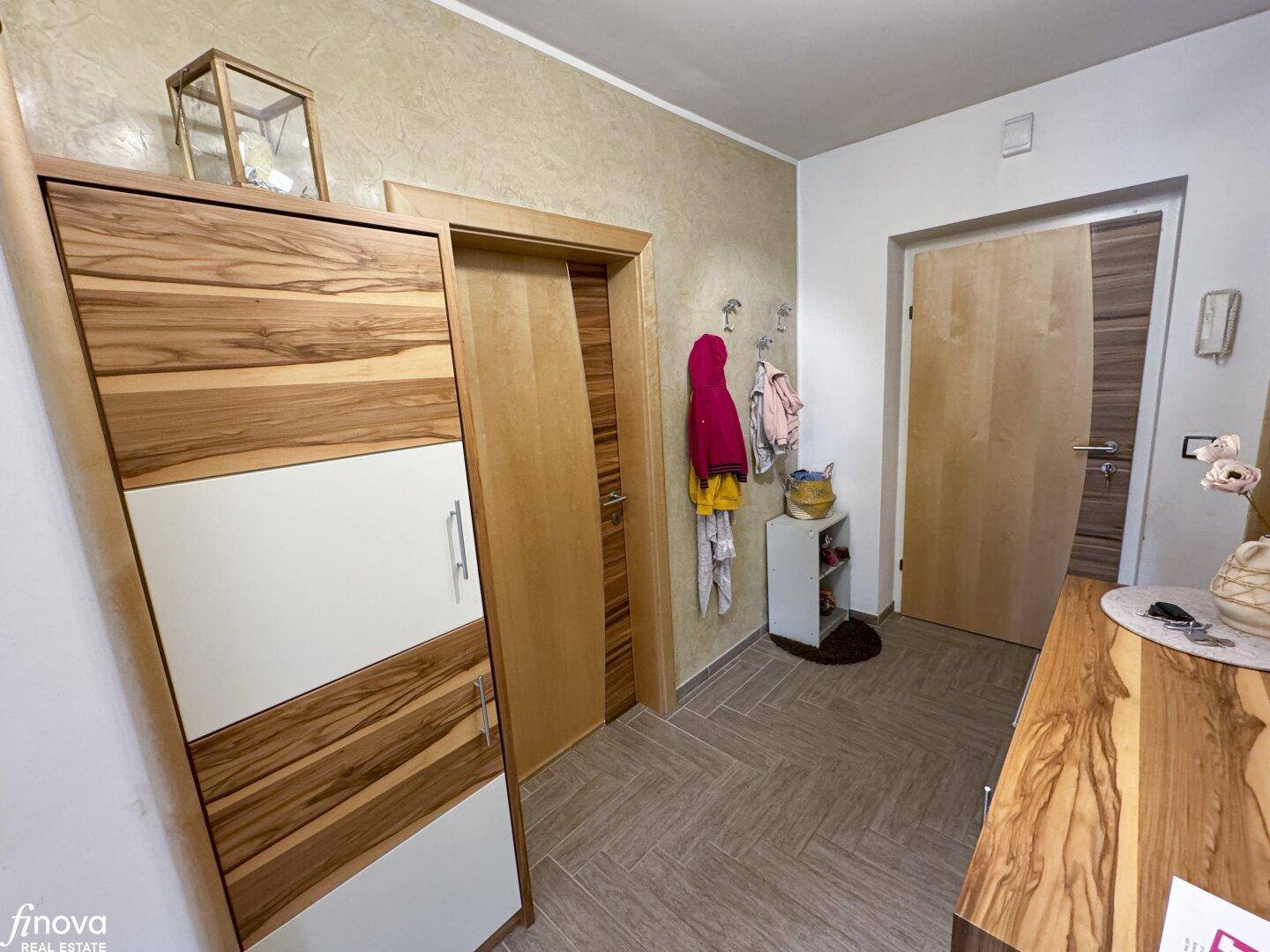 Eingangsbereich mit Garderobe, Holzschrank und gefliestem Boden, bietet praktischen Stauraum.