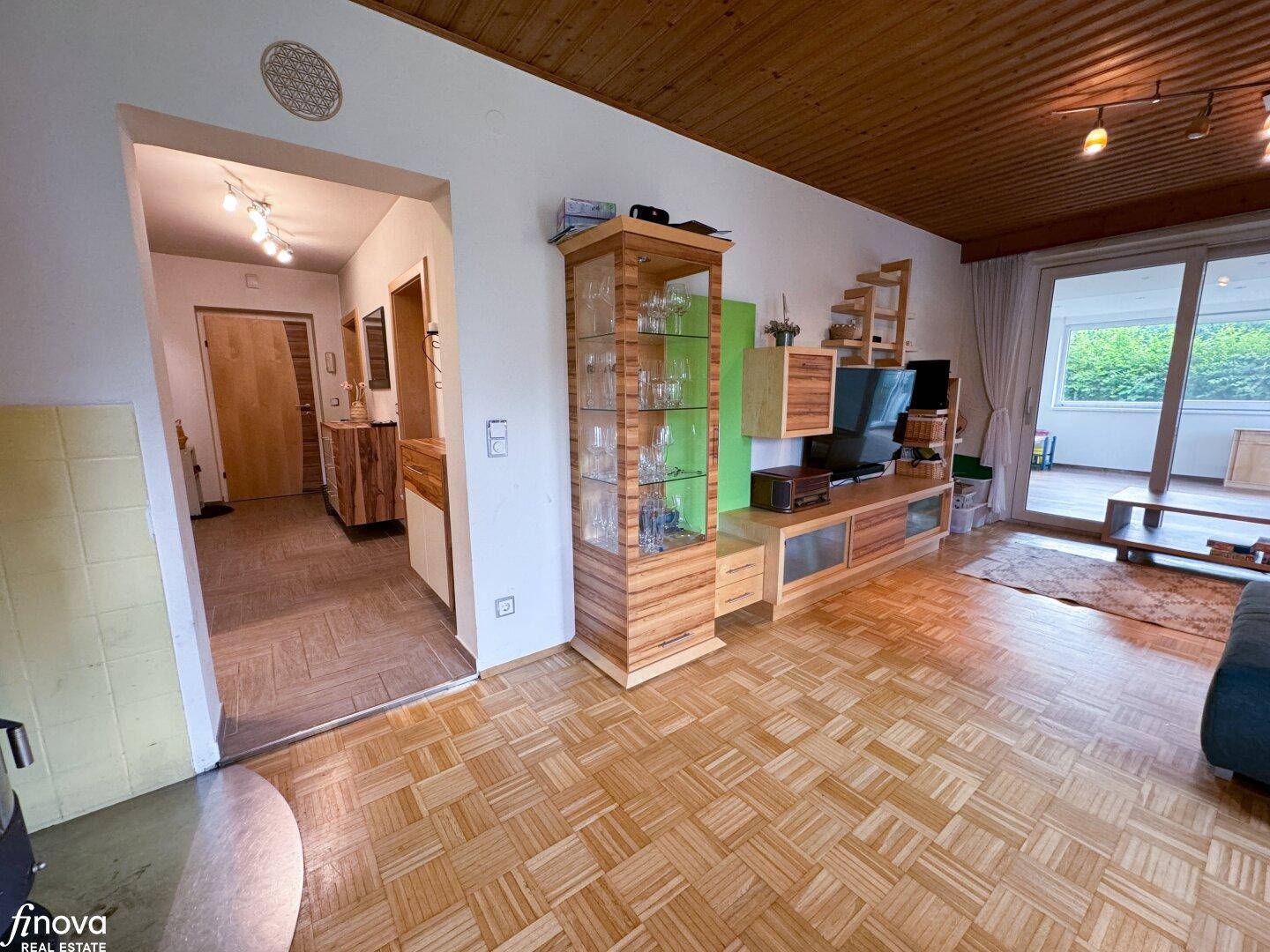 Geräumiges Wohnzimmer mit Parkettboden, Holzdecke und Blick in den Flur, hell und einladend.