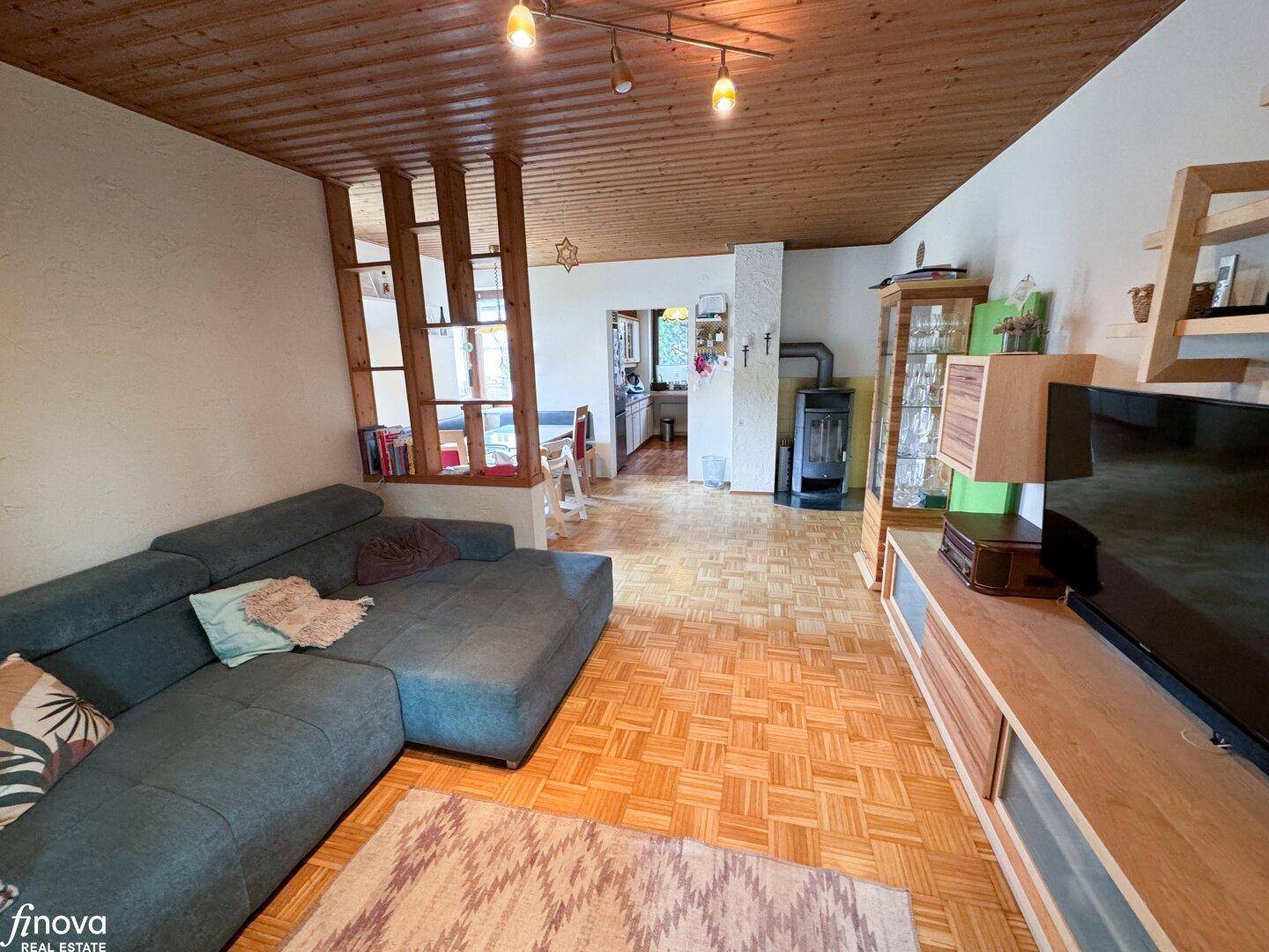 Wohnzimmer mit Ecksofa, Parkettboden und Kaminofen, ideal für entspannte Stunden.