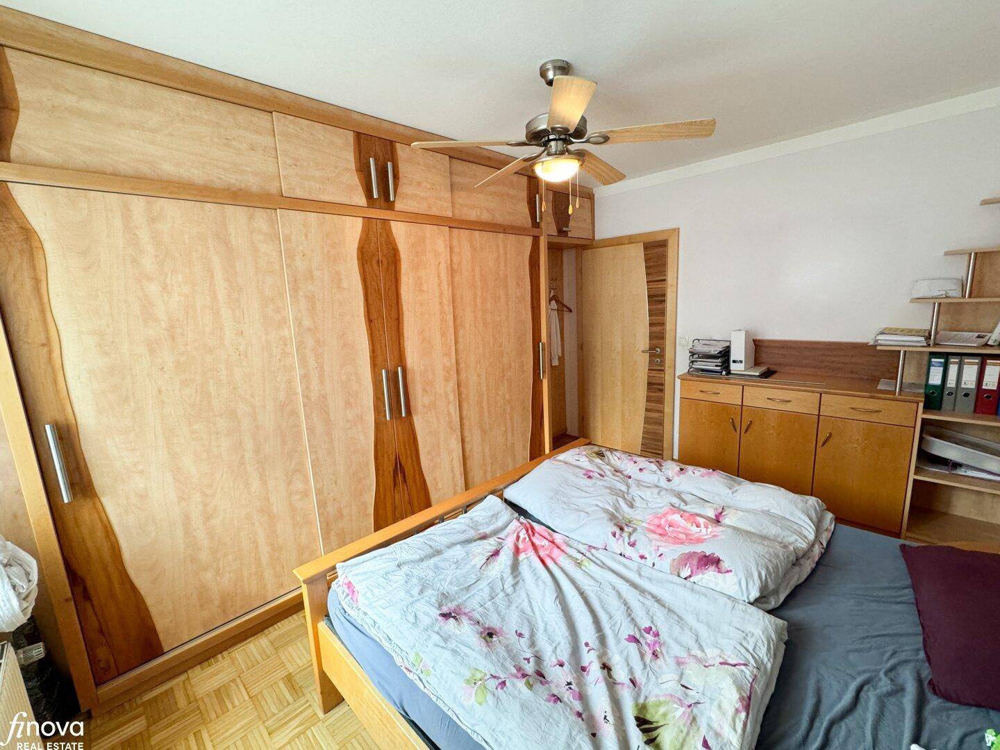 Schlafzimmer mit Einbauschränken, Doppelbett und Deckenventilator, bietet viel Stauraum.