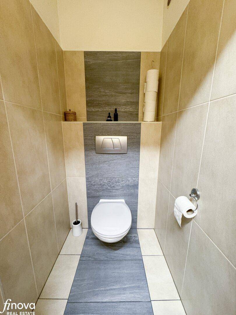 Modern geflieste Gästetoilette mit Wand-WC und Ablagefläche, sehr sauber und funktional.
