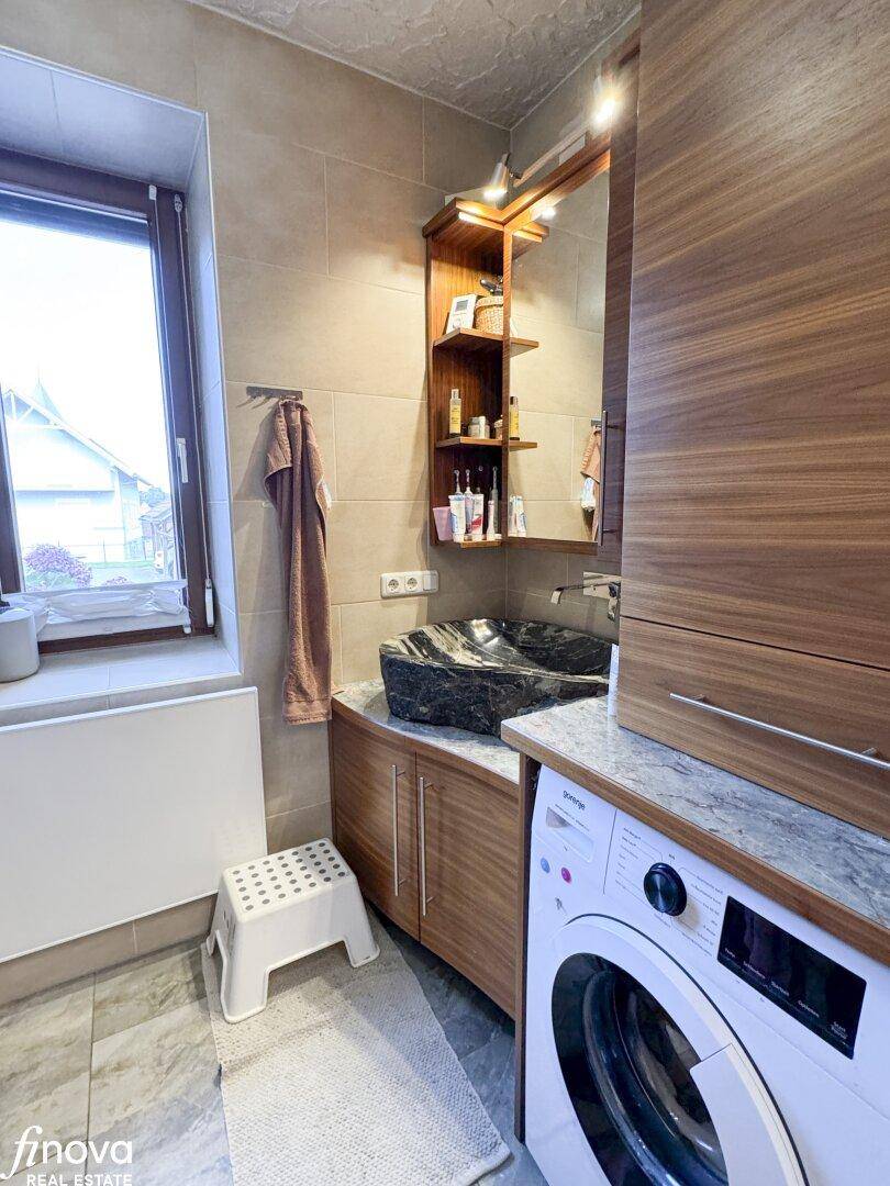 Badezimmer mit Waschbecken, Waschmaschine und Fenster, bietet praktischen Komfort.