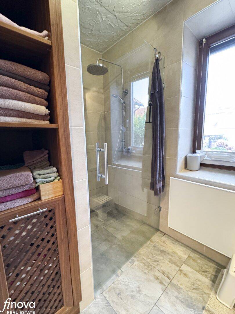 Badezimmer mit begehbarer Dusche, Fenster und Handtuchschrank, modern und hell.