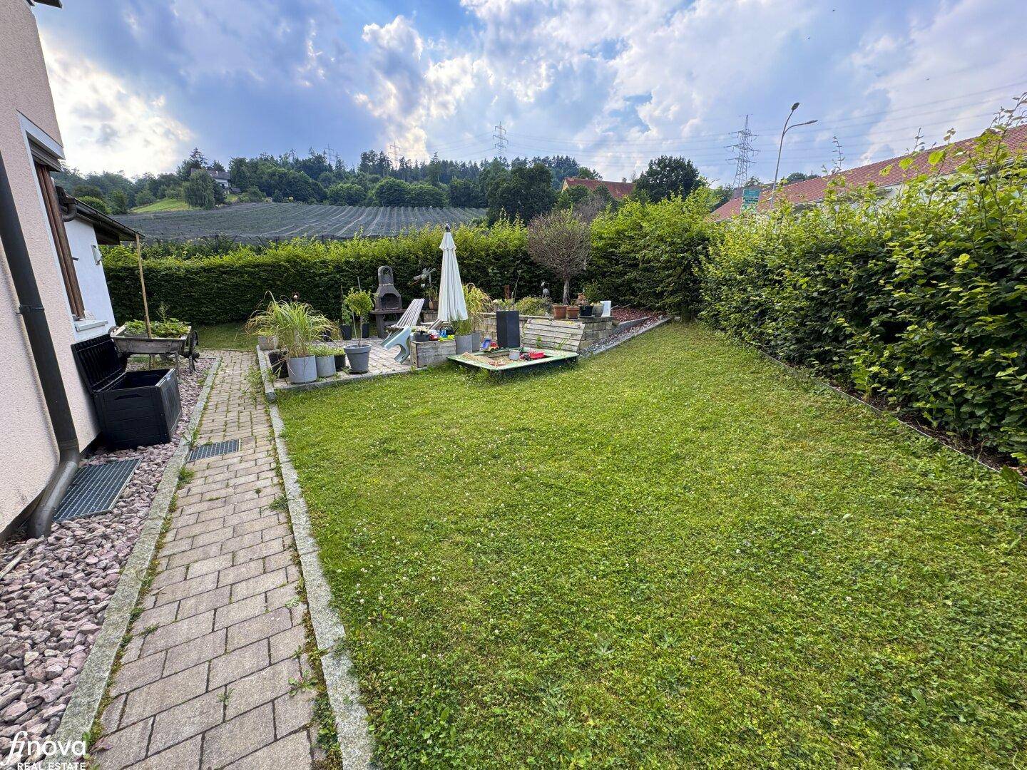 Gepflegter Garten mit Rasenfläche, Grillplatz und Hecke, bietet viel Platz im Freien.