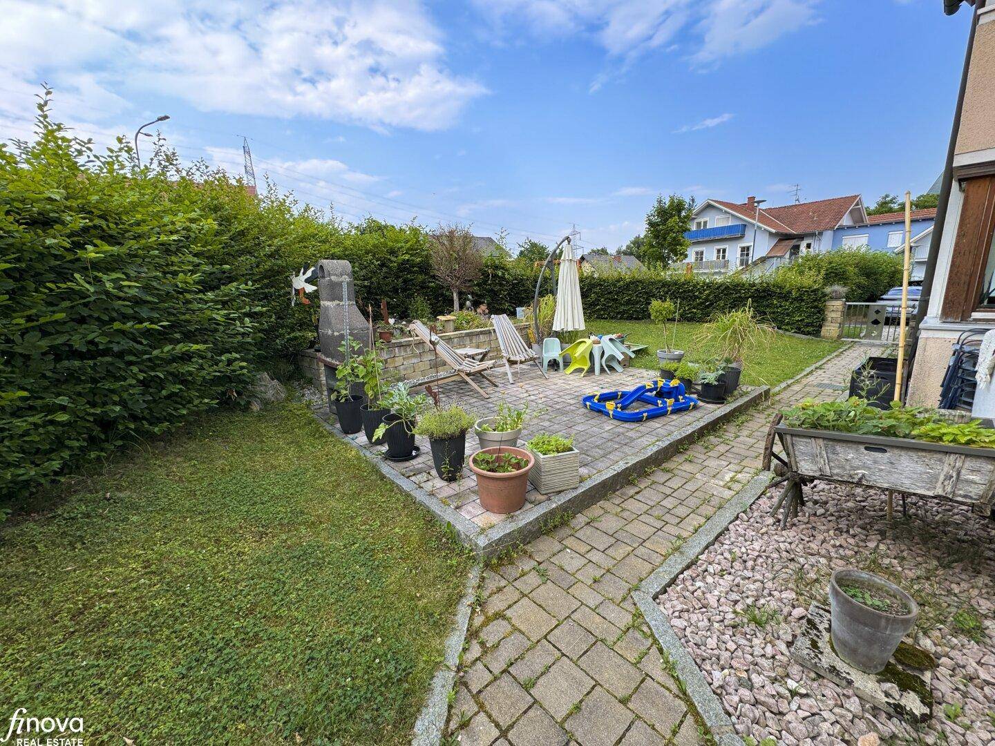 Garten mit gepflasterter Terrasse, Rasen und Grillbereich, perfekt für entspannte Stunden.