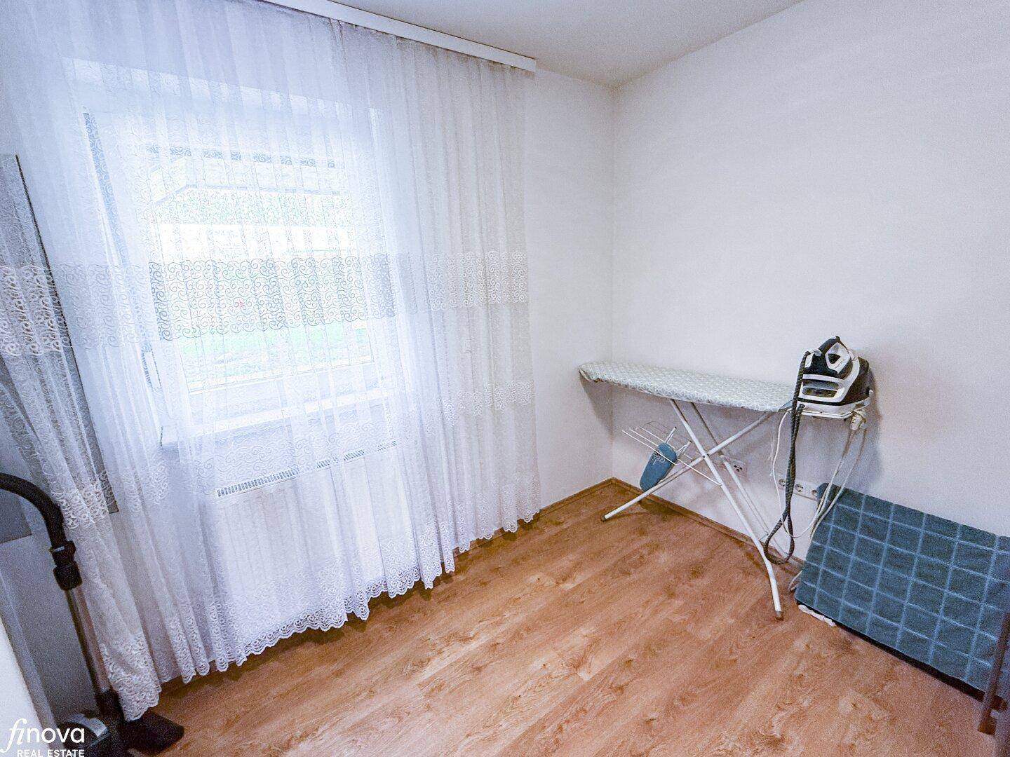 Praktischer Hauswirtschaftsraum mit Bügelbrett und Fenster, ideal für Haushaltsarbeiten.