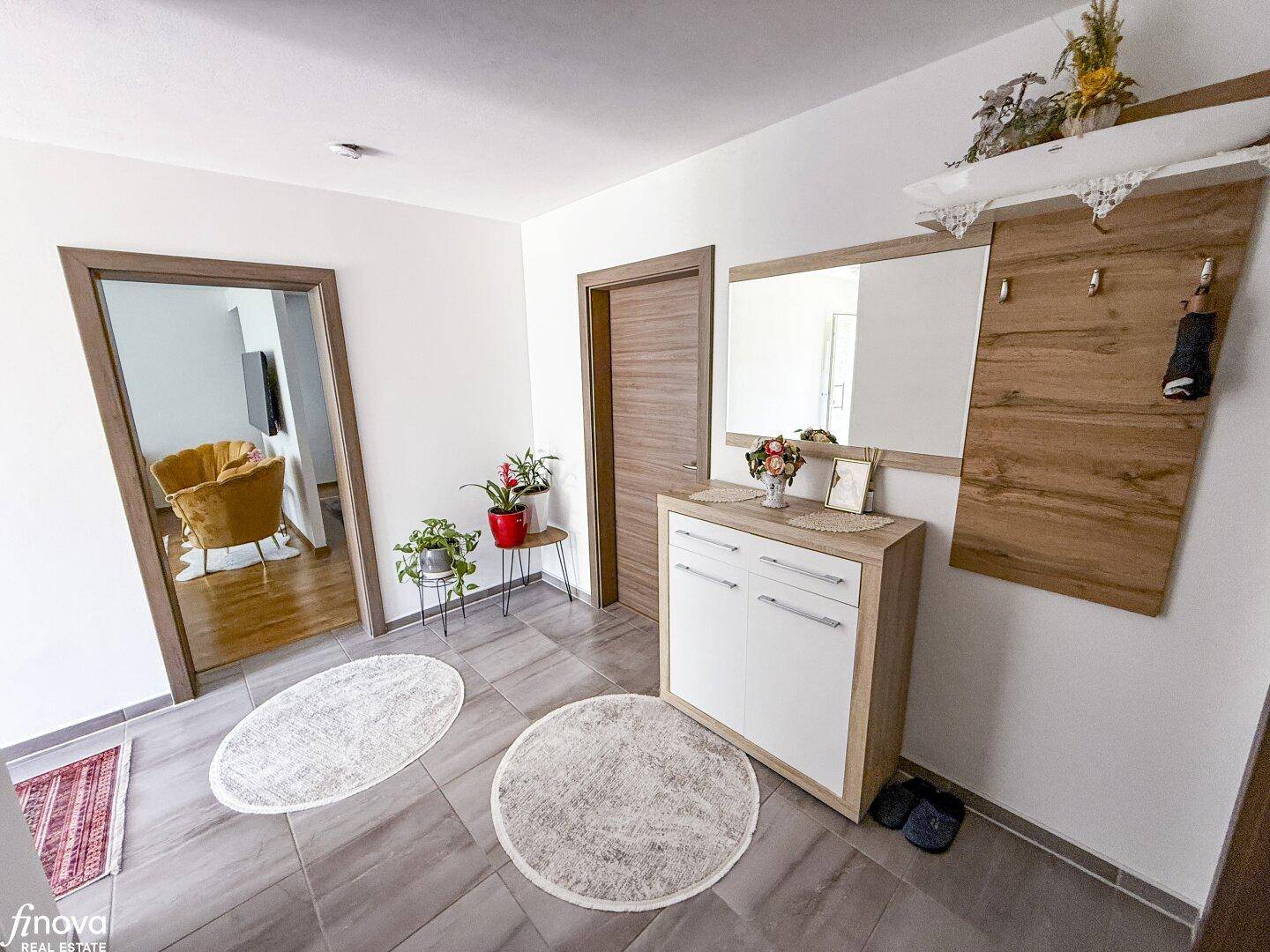 Eingangsbereich mit Garderobe, Spiegel und einem modernen Sideboard auf Fliesenboden.