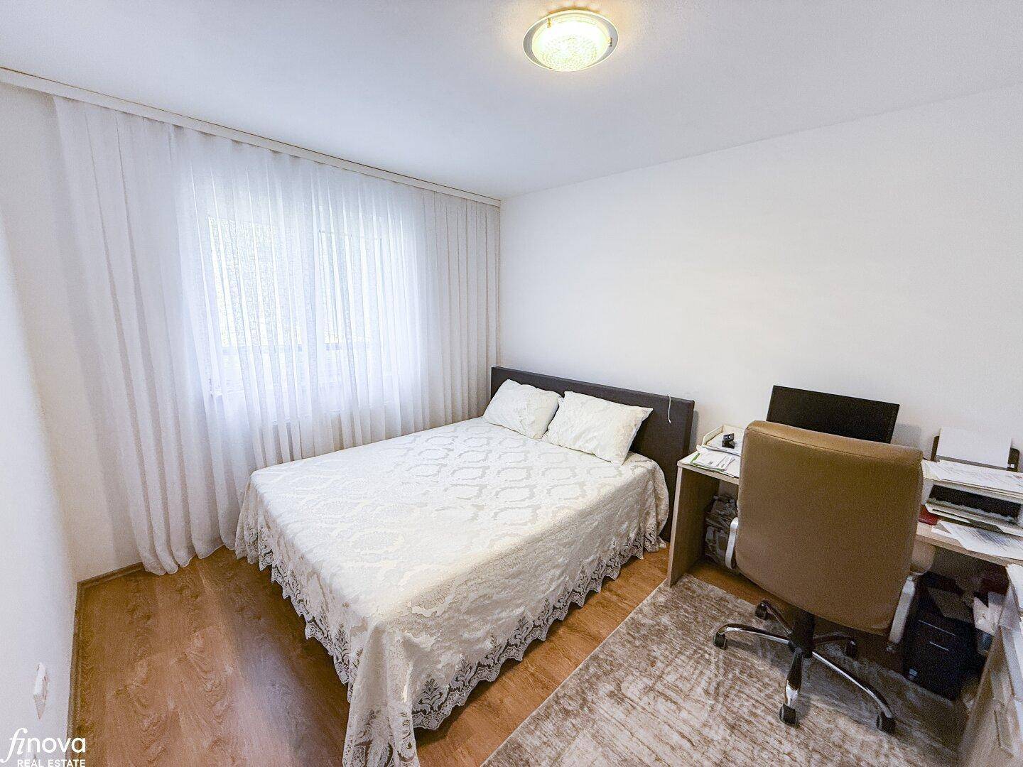 Schlafzimmer mit Bett und Schreibtisch, ideal als kombiniertes Schlaf- und Arbeitszimmer.