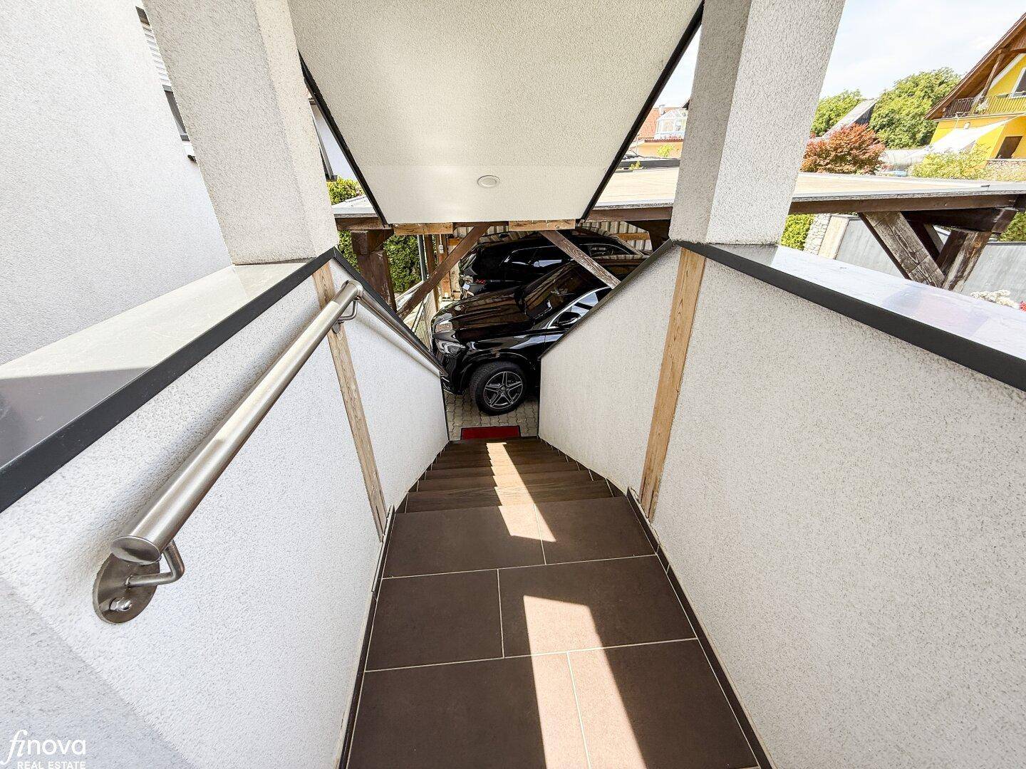 Treppe führt hinunter zu einem überdachten Parkplatz mit einem geparkten Auto.