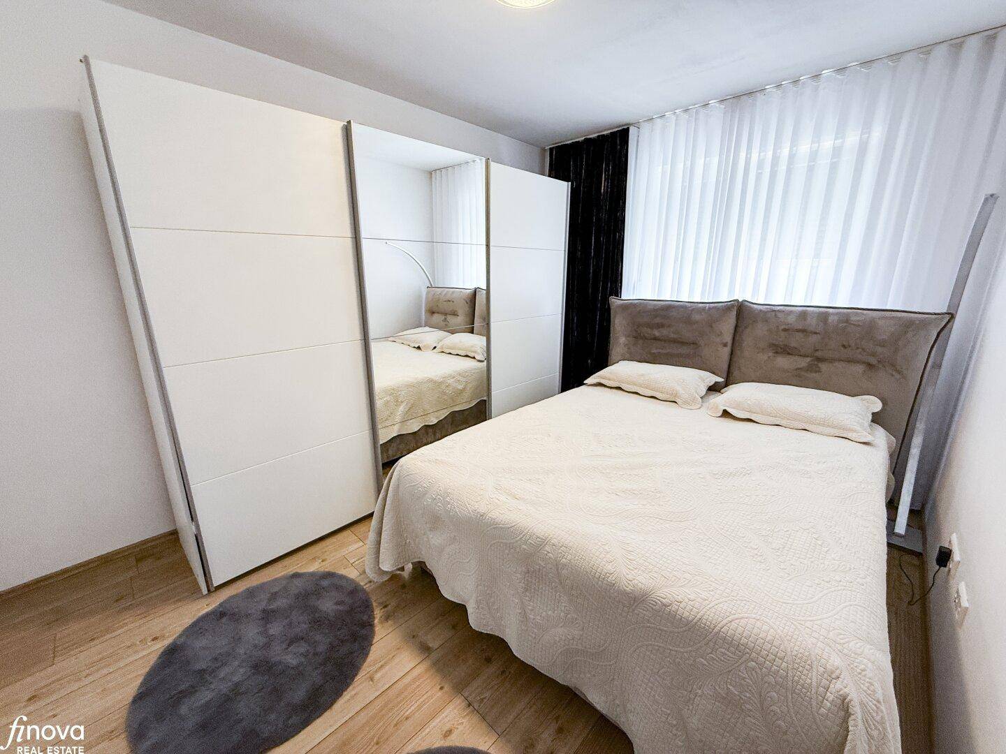 Schlafzimmer mit Doppelbett und großem Spiegelschrank, hell und modern eingerichtet.