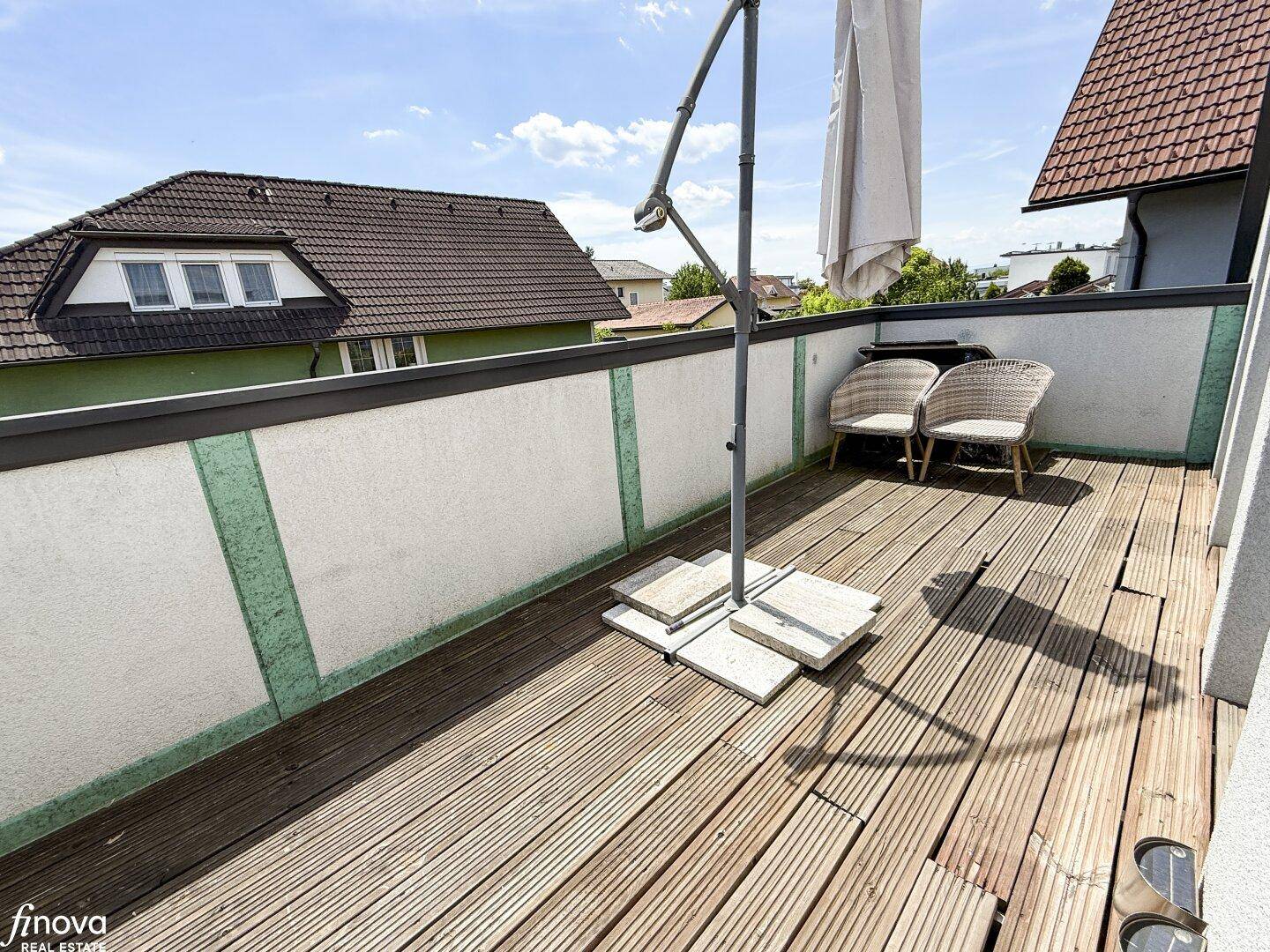 Geräumiger Balkon mit Holzbelag, Sonnenschirm und Sitzgelegenheiten für Entspannung.