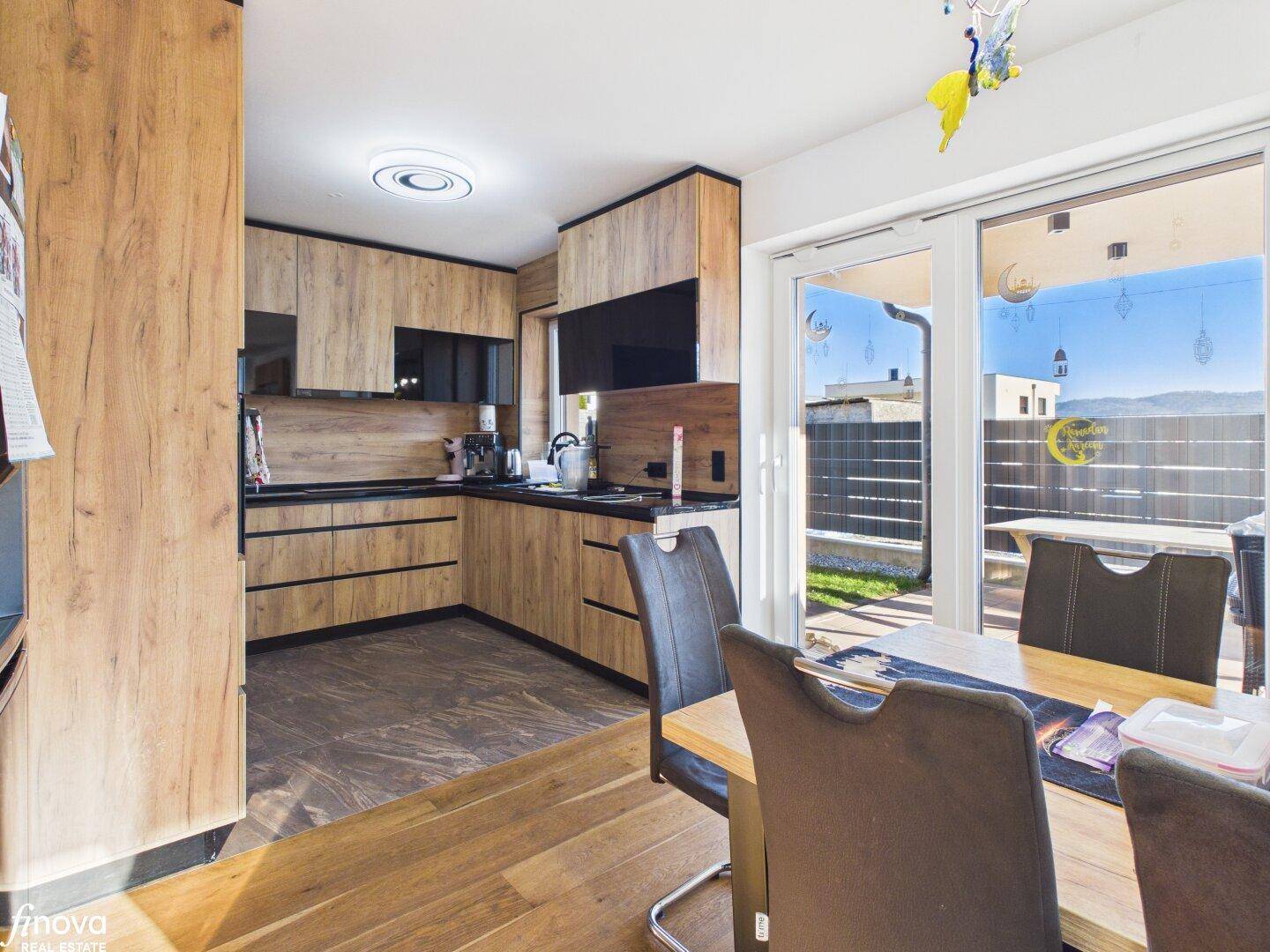 Moderne Holzküche mit dunklen Arbeitsplatten und direktem Zugang zur Terrasse.