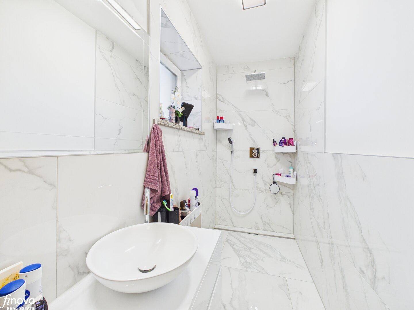 Modernes Badezimmer mit Marmorfliesen, ebenerdiger Dusche und ovalem Waschbecken.