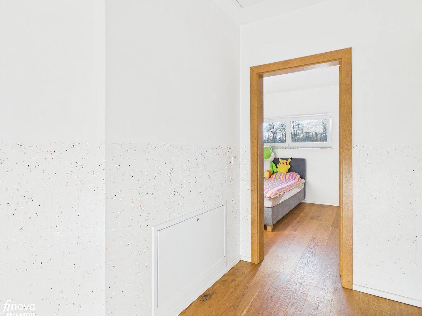 Flur mit Holzboden und Zugang zu einem weiteren Schlafzimmer.